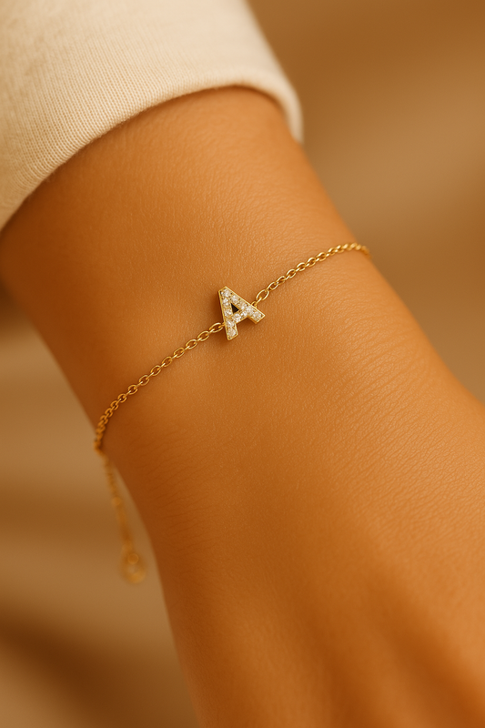 Close-up of a woman’s wrist wearing a delicate 14K yellow gold diamond initial bracelet featuring the letter A with pavé-set natural diamonds on a fine cable chain