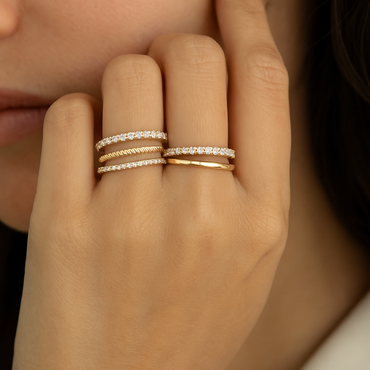 Close-up of a hand wearing two gold rings with diamond bands.