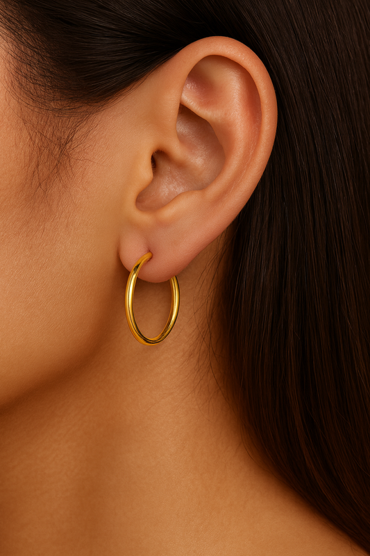 Close-up of an ear wearing a gold hoop earring with dark hair.