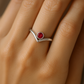 Close-up of a woman’s hand wearing a 14K gold Bezel-Set V Birthstone Ring featuring a natural round ruby, showcasing the elegant split-shank design and polished finish
