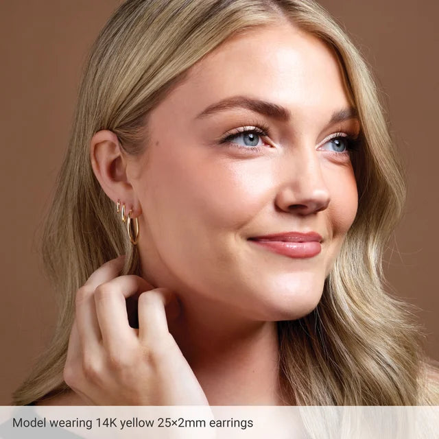 model wearing 25 mm 3 mm thick 14K yellow gold tube hoop earrings

